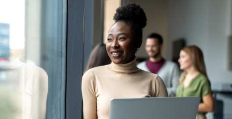 Woman in beige turtleneck sitting at a desk with a laptop image