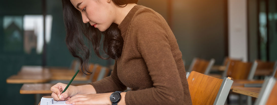 Woman sitting at desk in a classroom taking a test image