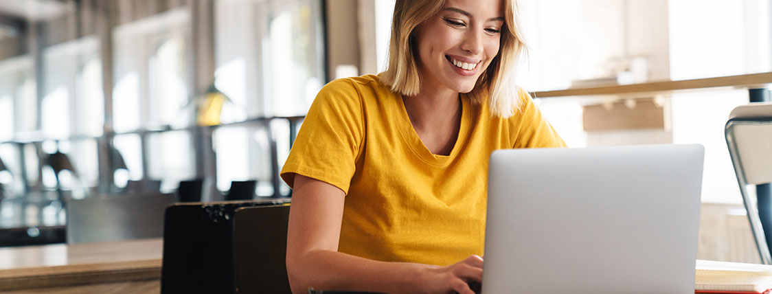 Woman working on a laptop at a table in an open office area image