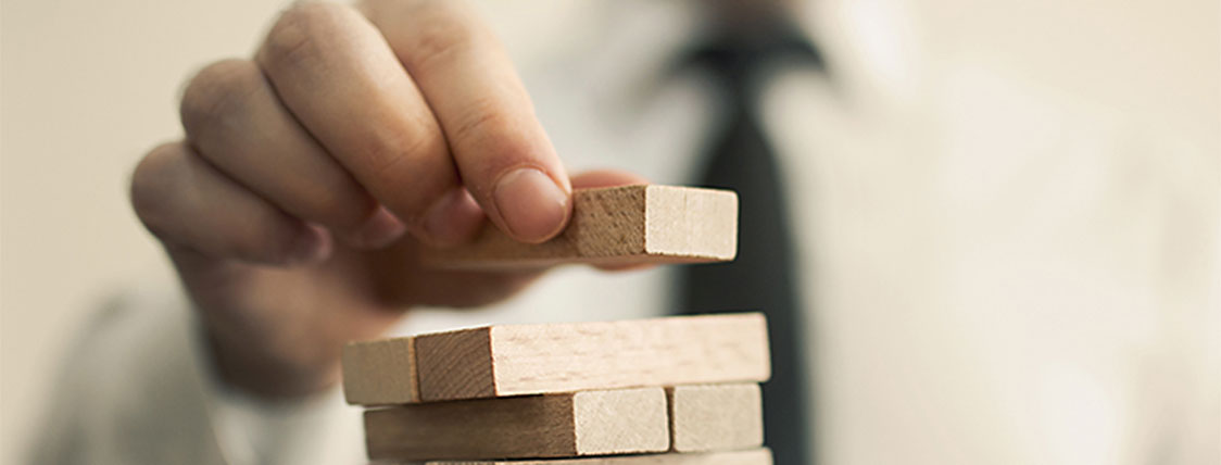Man stacking wood blocks representing what it takes to become a CFA charterholder