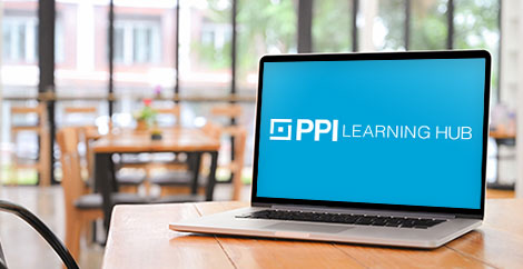 Laptop with PPI Learning Hub logo on screen on a table in a coffee shop image