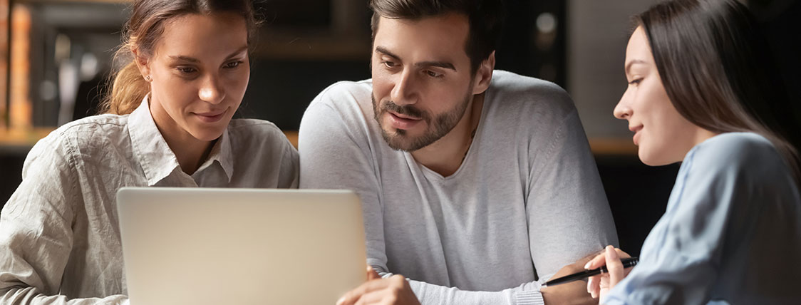 Three colleagues looking at a laptop screen together image