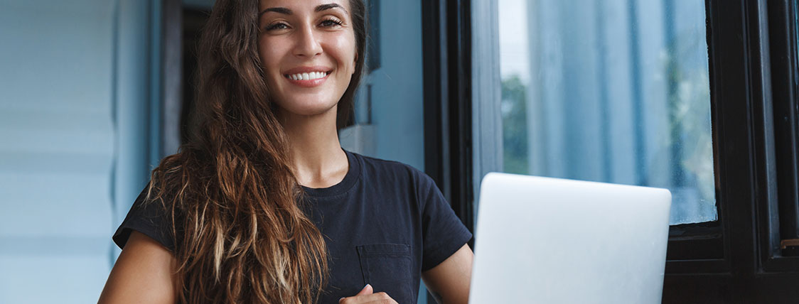 Woman working on a laptop next to a window image