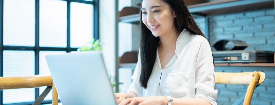 Woman sitting at a desk in an open office area working on a laptop image