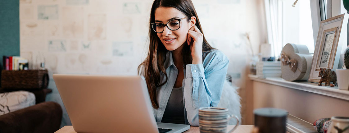 Woman seated at her desk in a home office working on a laptop image
