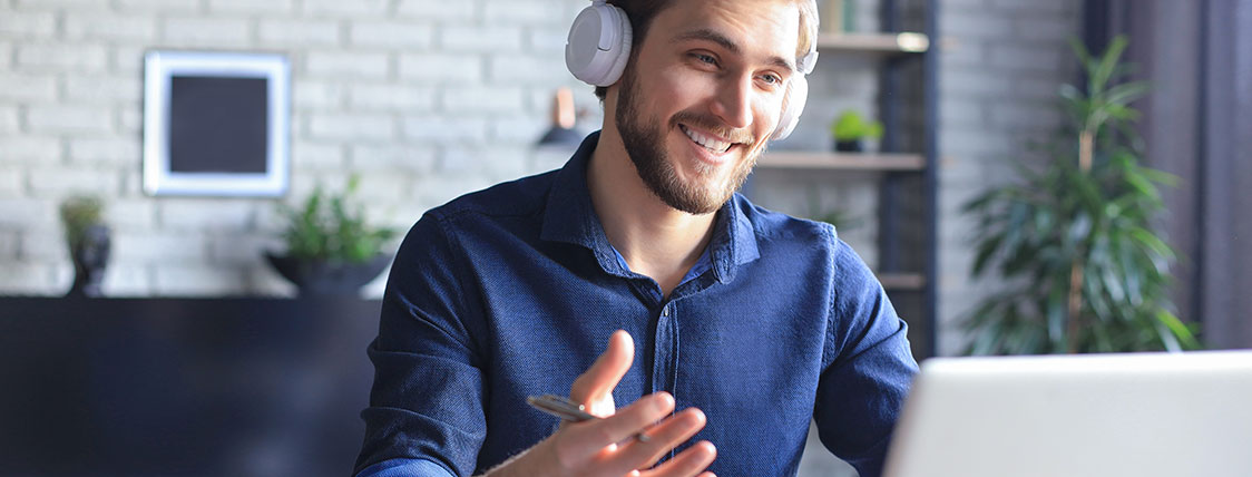 Man wearing headphones and sitting in front of an open laptop image