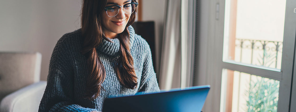 Woman in her living room working on a laptop in front of a window image