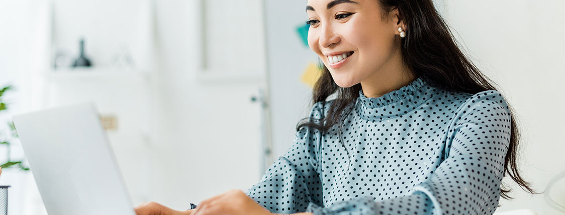 Woman in blouse with polka dots working on laptop image