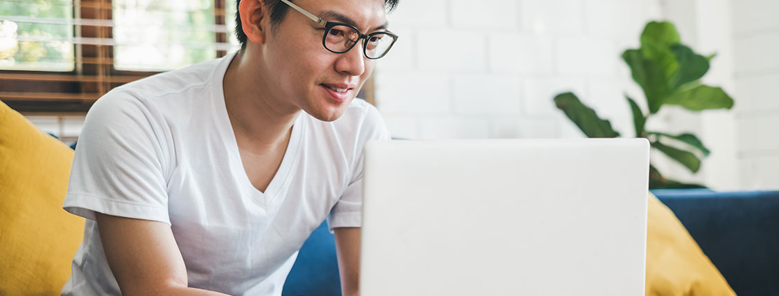 Man sitting on a couch and working on a laptop image