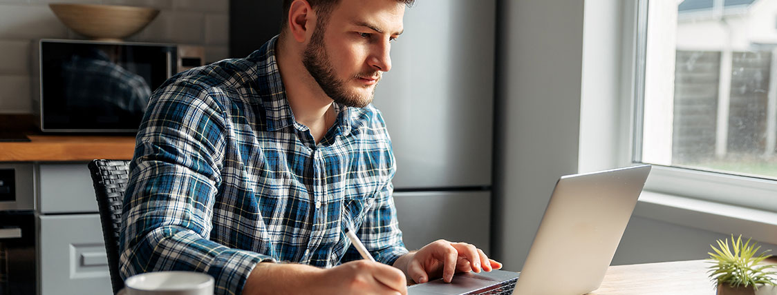Man sitting at a desk looking at a laptop image