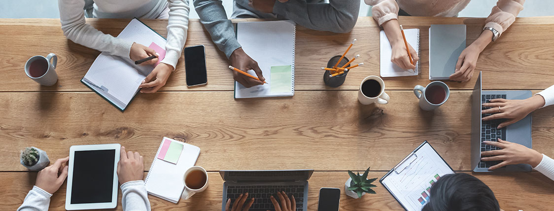 Top down view of multiple colleagues working together at a conference table image