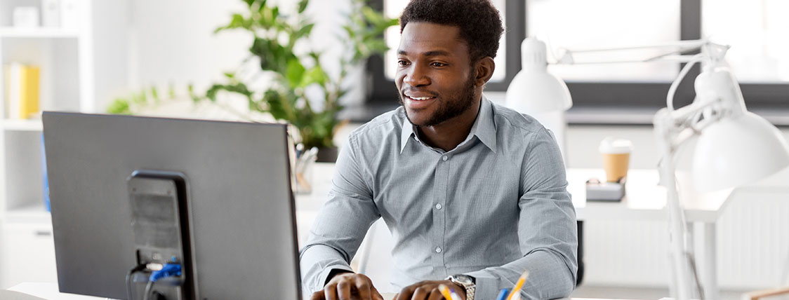 Man sitting at a desk in front of a computer monitor in an office image