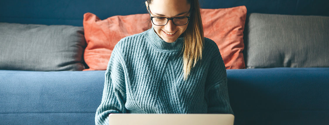 Woman seated in front of a sofa and working on a laptop image