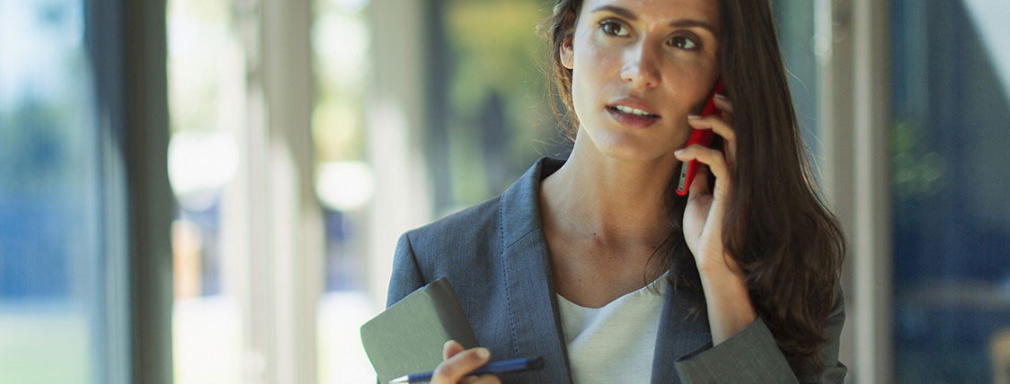 Woman holding a notebook and walking while talking on a phone image