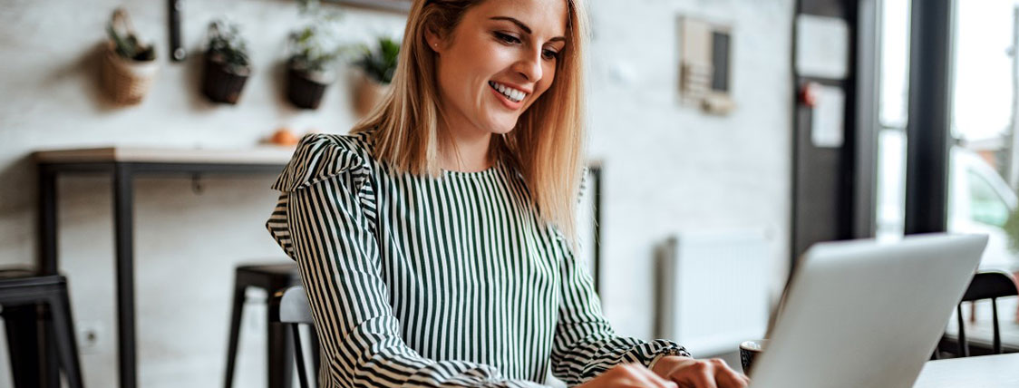 Woman sitting at a table working on a laptop in a casual office area image