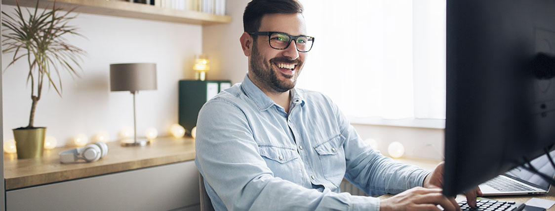 Man sitting at desk in office in front of computer monitor image
