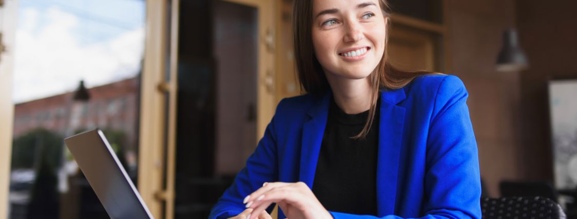 Woman in blue blazer working on a laptop in an office image