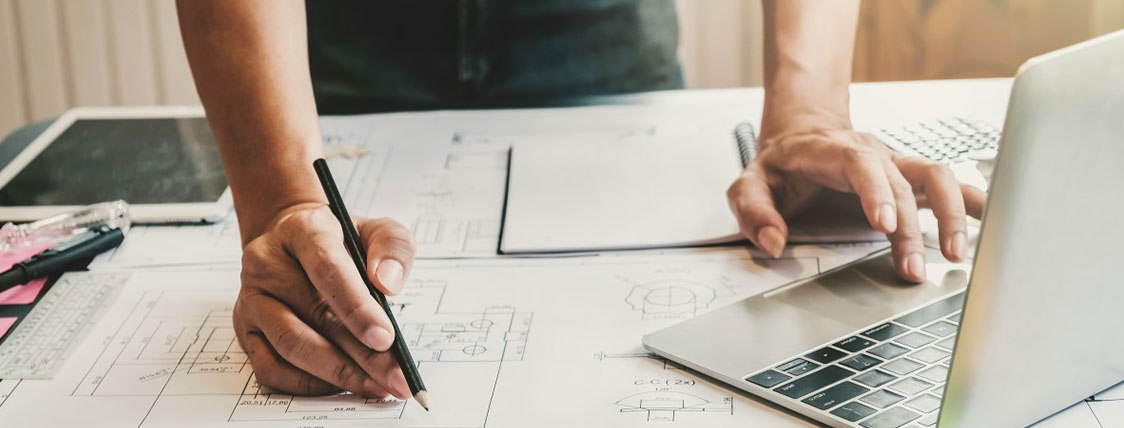 Person working with blueprints and an open laptop on a table image