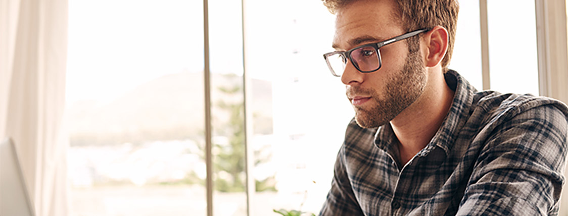 Man using laptop to view the most Frequently Asked Questions About Level III of the CFA Exam