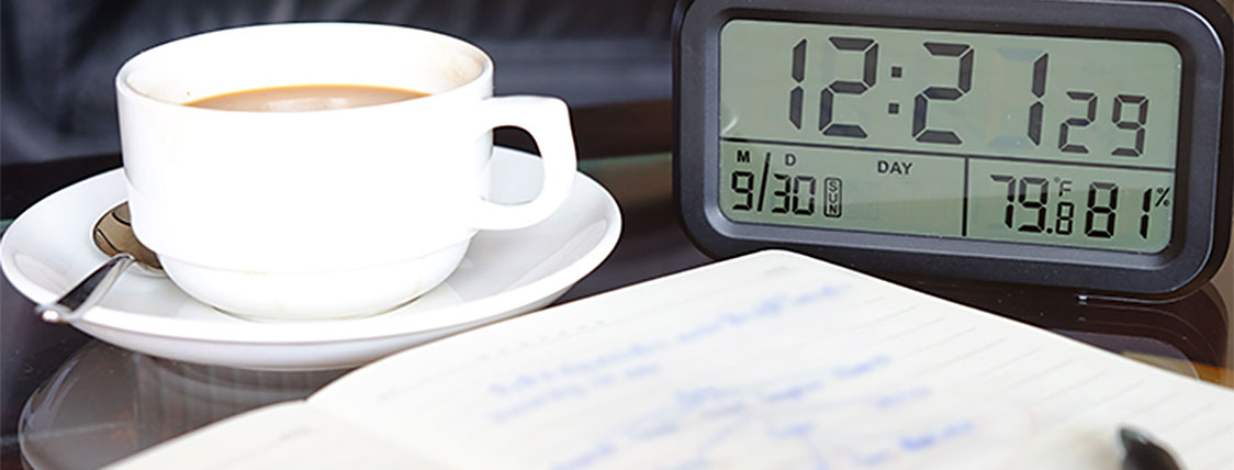 Notes, coffee, and clock for studying for CFA Exam while working full time