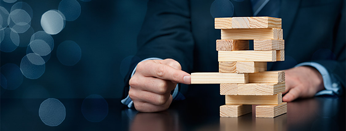 A man analyzing risk of move in Jenga game illustrates the need for consideration before you decide to sit for the FRM exam
